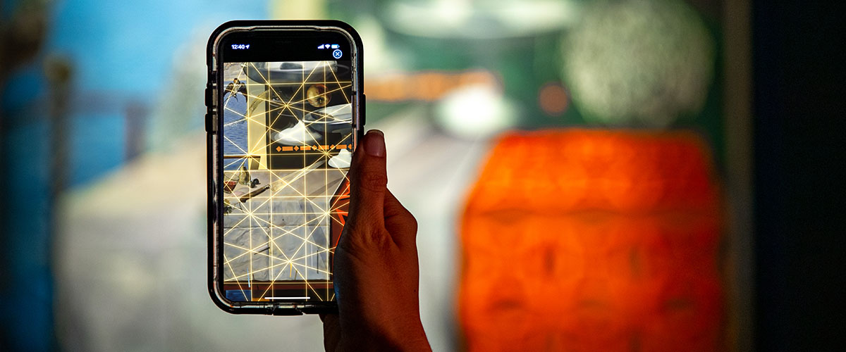 Photograph of person holding phone and scanning one of Dalí's paintings