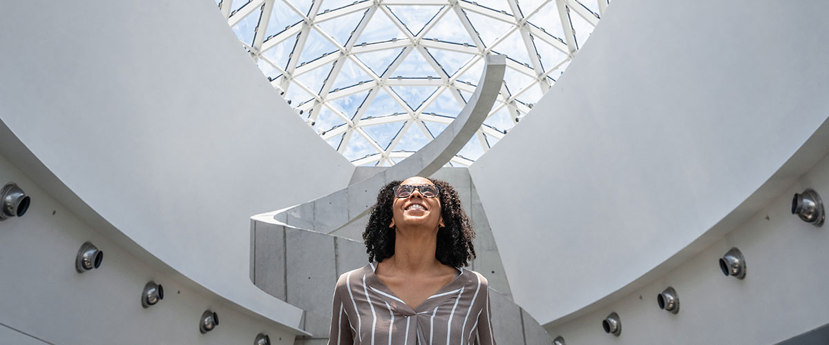 Woman stands in front of The Dali's helical staircase