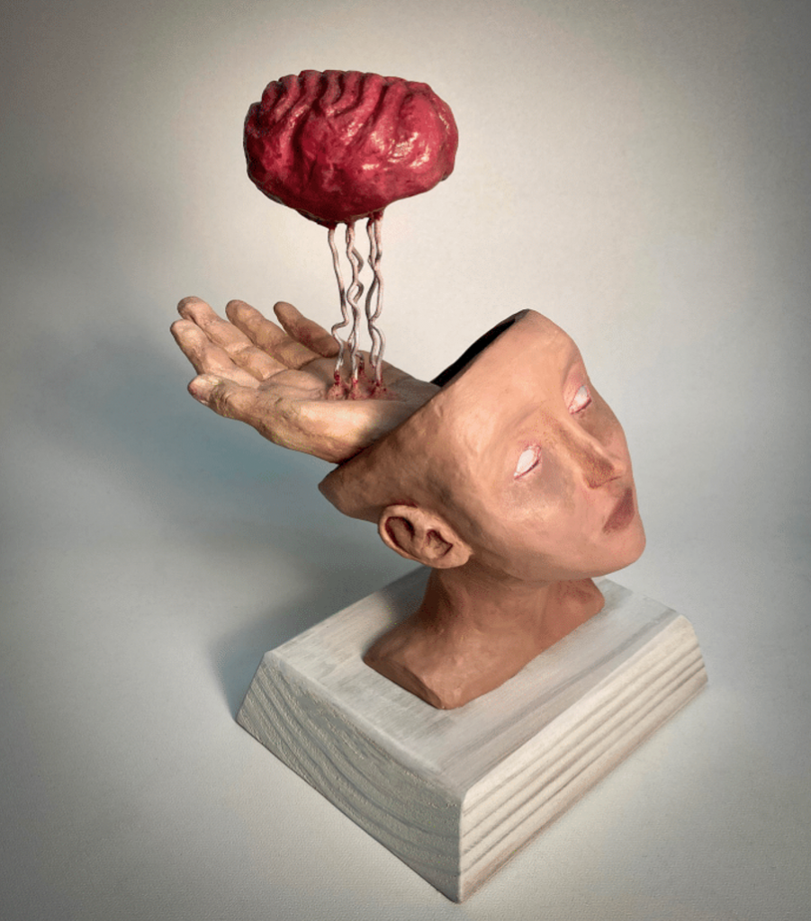 A statue of a head and a hand, with a brain above them