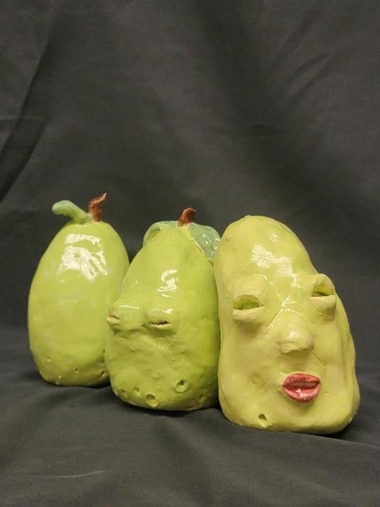 Three peaches with carved eyes and a lip