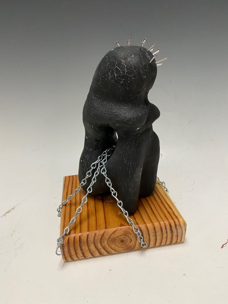 A small statue sitting and pondering in chains