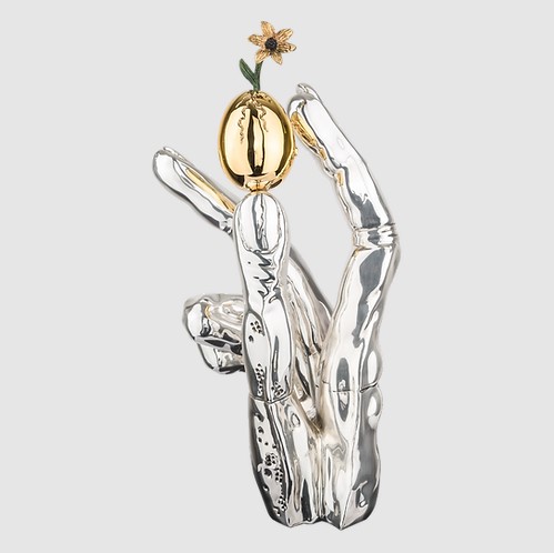 Silver and gold statue of a hand holding a golden egg with a budding flower