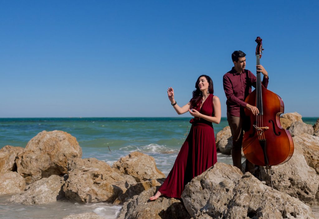 Orilla Musical Group poses with instruments on rocky coastline