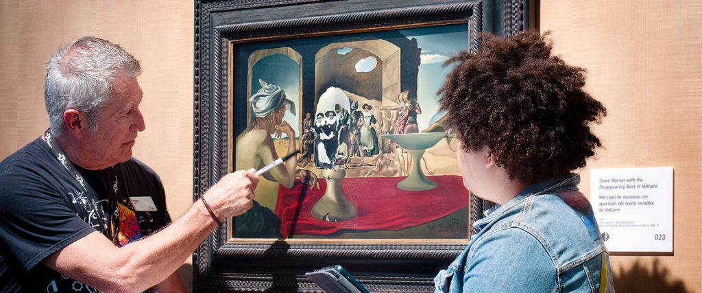 Professor points to detail on Dalí painting while student observes