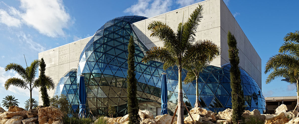 a building with a curved glass wall and palm trees