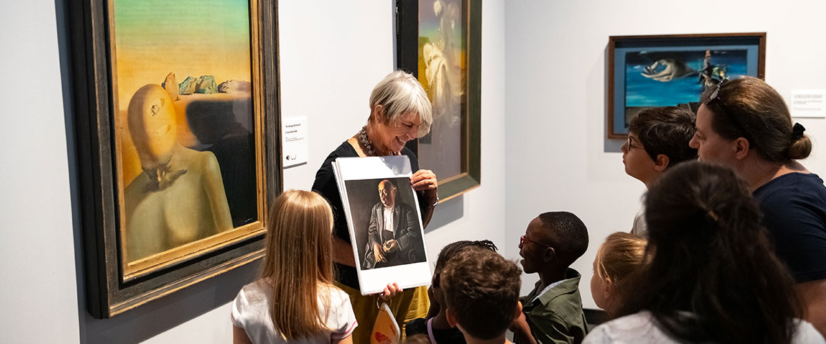 a person holding a picture of a person in a room with kids