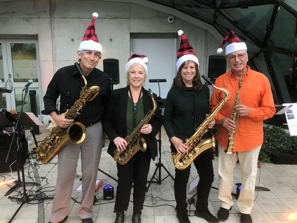 group of four people wearing holiday hats and holding instruments