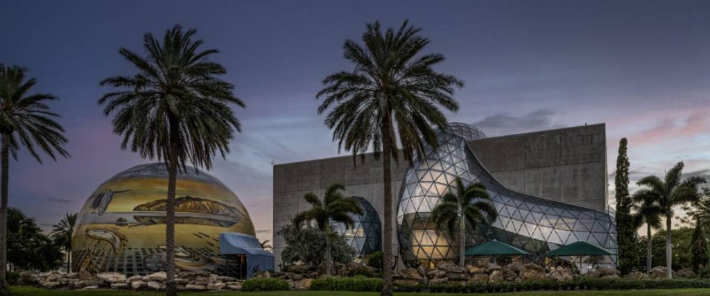 a building with palm trees in front and dark night sky